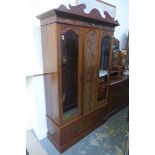 An Edwardian walnut mirrored wardrobe with central carved panel, raised on a single drawer base.