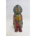An unusual clockwork tinplate figure of a native American with feathered headdress clutching a