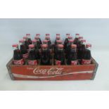 A Coca-Cola branded wooden crate with a full set of 24 Coca-Cola bottles inside.