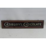 A Cadbury's Chocolate glass advertising sign in original wooden frame, 23 x 4 1/2".