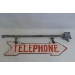 An enamel red and cream double sided directional Telephone enamel sign on a hanging bracket, the