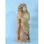 An oriental carved soapstone figure of Quan Yin, standing, holding a vase of flowers, 15in (38cm)