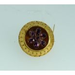 A circular Brooch, with ropework pattern border, the concave centre set amethyst coloured stone