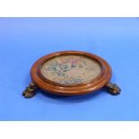 A Victorian mahogany Table Stand, formed of a wool-work panel in a glazed circular moulded