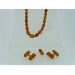 A small string of graduated oval Amber Beads, with damaged gilt metal clasp, together with a