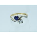 A diamond and sapphire cross-over ring, the shaped shoulders set with small diamonds, all mounted in