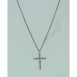 A small diamond set Cross, of eleven circular cut closed backed diamonds, on a white gold chain