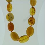 An Amber Necklace, formed of thirteen large vari-coloured beads, the clasp marked 375, approx