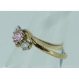 A pink sapphire and diamond cross-over Ring, mounted in 9ct yellow gold, Size P.