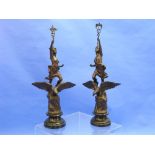 A pair French bronzed spelter figures standing on eagles perched on rocks, on turned ebonised wood