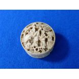 A late 19thC carved ivory circular Box, decorated with figures, 1?in (3.5cm) diameter, containing