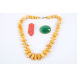 An early 20th Century, possibly Tibetan, amber necklace, a jade brooch and a coral carved brooch (
