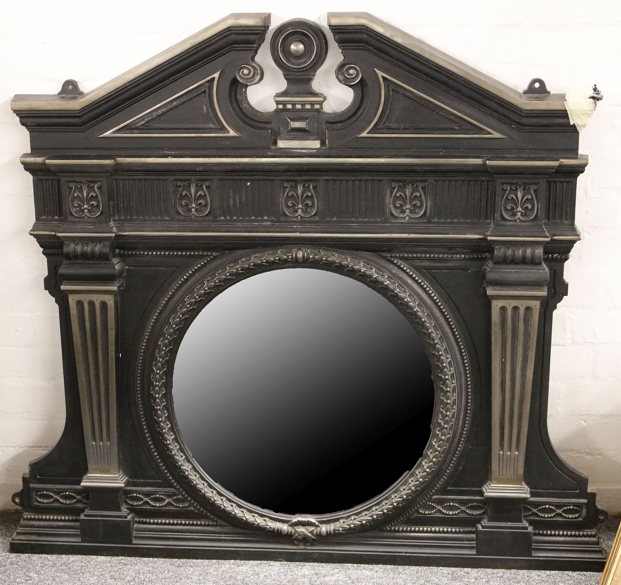 A late Victorian cast iron overmantle, having decorative pediment to top and containing a circular