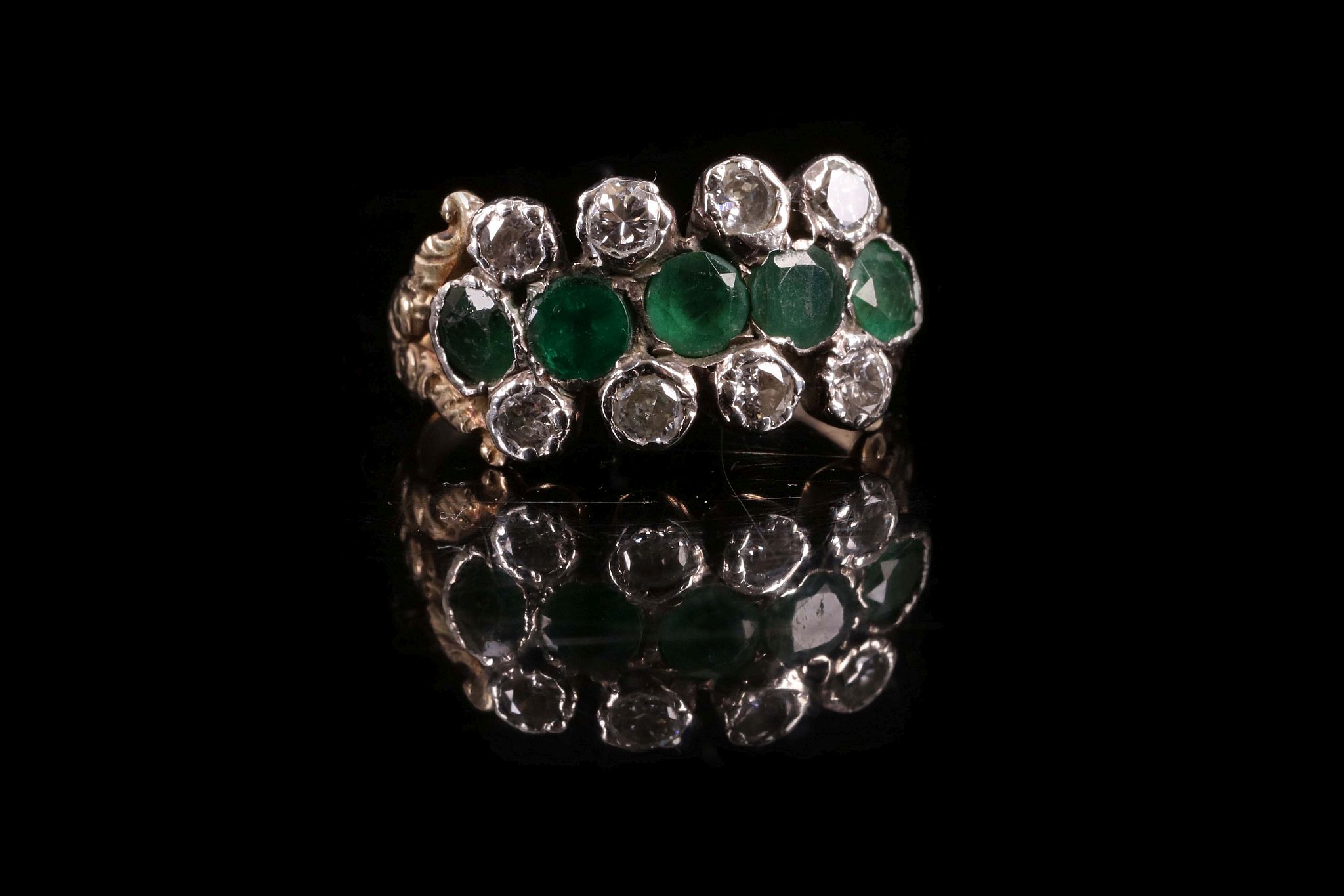 An antique style emerald and diamond ring, set with central band of 5 emeralds flanked by four