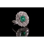 An 18ct white gold, emerald and diamond set cluster ring.