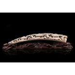 A 19th Century Japanese signed carved ivory tusk depicting village and domestic life, supported on a