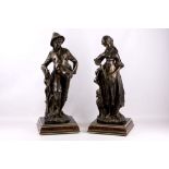 A 20th Century pair of bronzed figures of a man with umbrella and a girl with dog, supported on