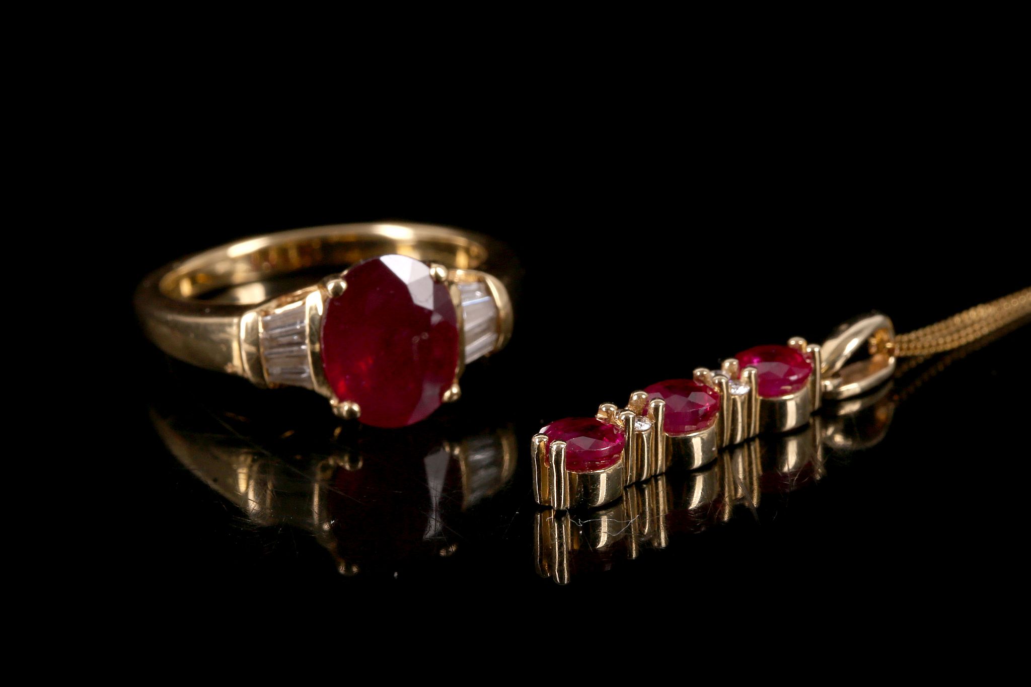 An 18 carat yellow gold, diamond, and ruby ring, set oval cut ruby of approx. 20. carats, flanked by