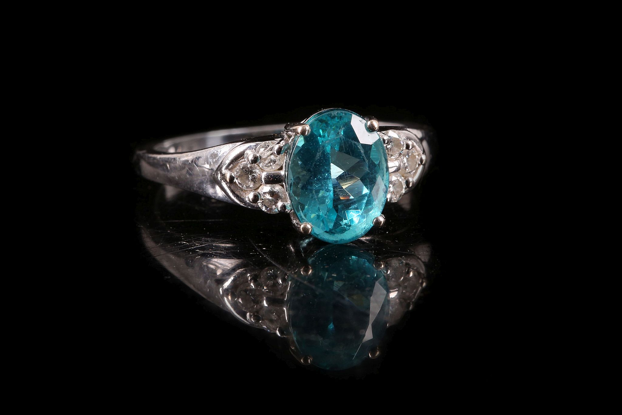 An 18 carat white gold, diamond and blue apatite ring, set oval cut apatite flanked by six round cut