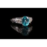 An 18 carat white gold, diamond and blue apatite ring, set oval cut apatite flanked by six round cut