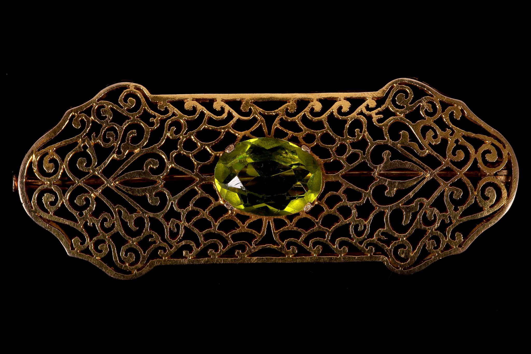 An openwork brooch with synthetic green stone Centrally set with an oval-cut synthetic green