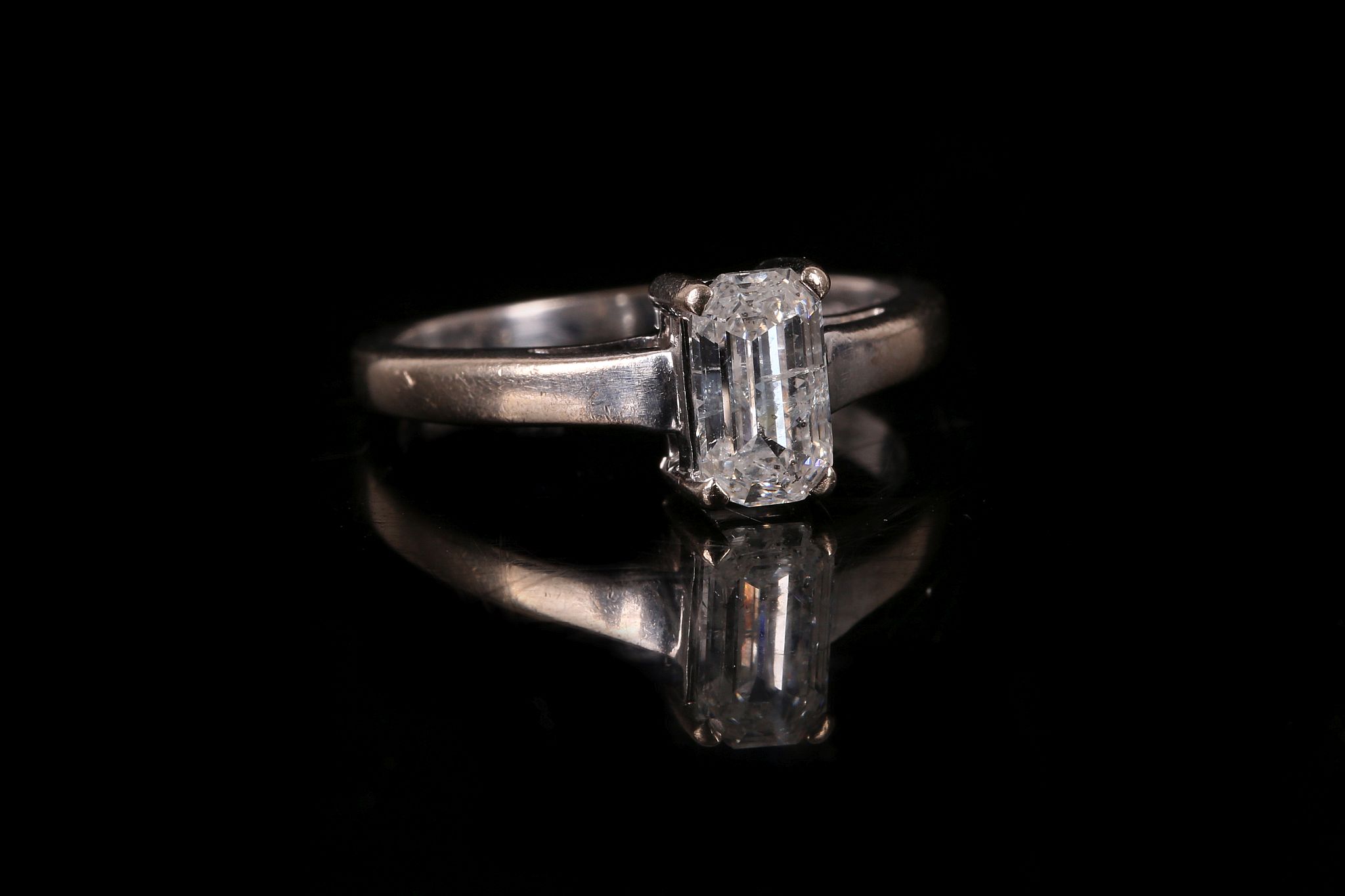 A diamond single-stone ring The cut-cornered step-cut diamond, in a four-claw setting, to an 18