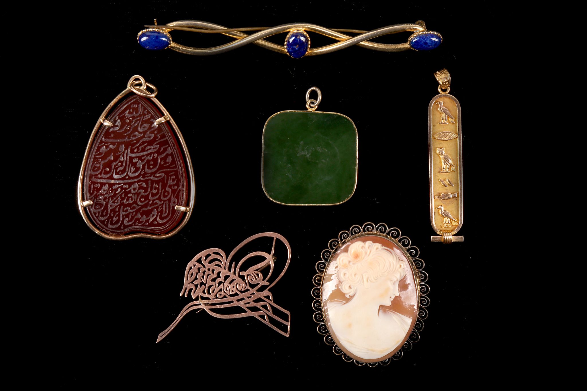 A collection of jewellery Including a pendant with Egyptian figures, a green hardstone pendant, a