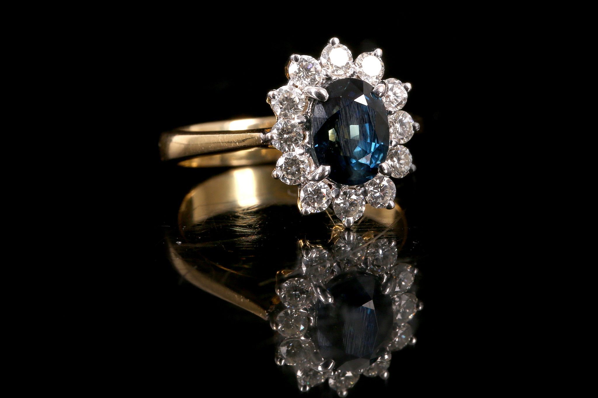 A sapphire and diamond cluster ring The oval-cut sapphire within a surround of brilliant-cut