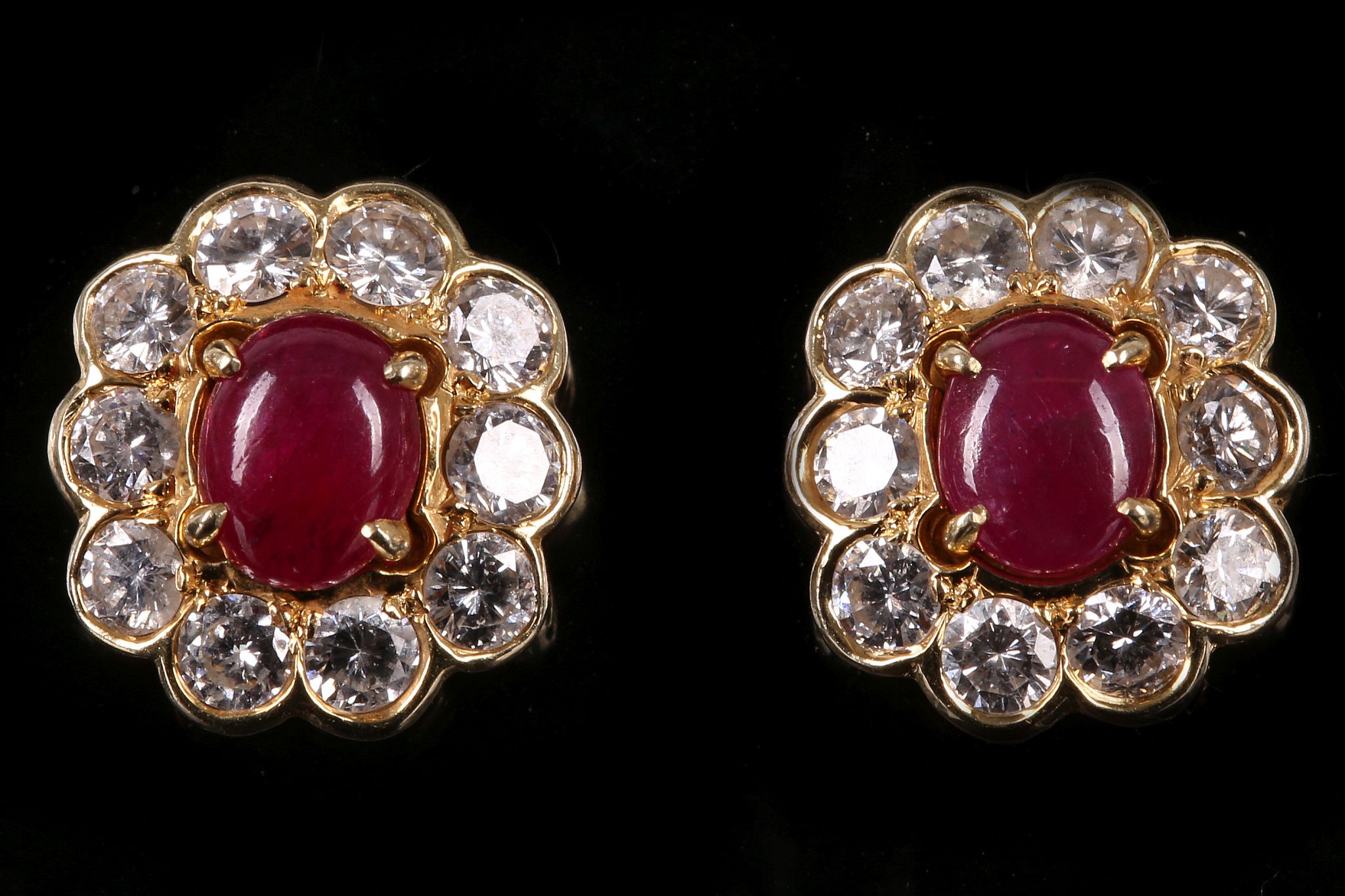 A pair of ruby and diamond earstuds Each central oval cabochon ruby, within a detachable surround of