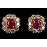 A pair of ruby and diamond earstuds Each central oval cabochon ruby, within a detachable surround of