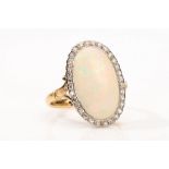 An opal and diamond ring The oval opal, framed by single-cut diamonds, between fleur-de-lis