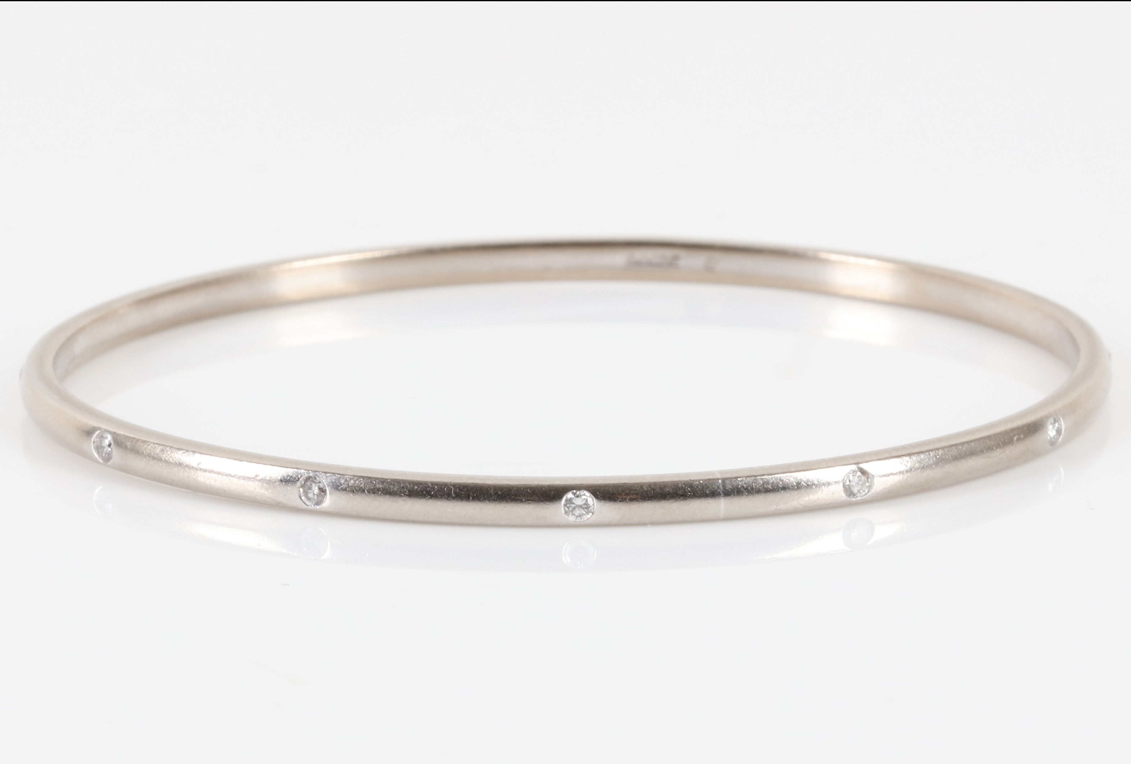 A white gold and diamond bangle, by Theo Fennell The thin brushed 18 carat white gold bangle set