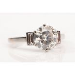 A diamond single-stone ring  The brilliant-cut diamond, in a six-claw setting, between baguette-