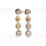 A pair of yellow sapphire and diamond pendent earrings The clusters of oval-cut sapphires, graduated