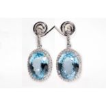 A pair of blue topaz and diamond pendent earrings Each oval-cut blue topaz within a brilliant-cut