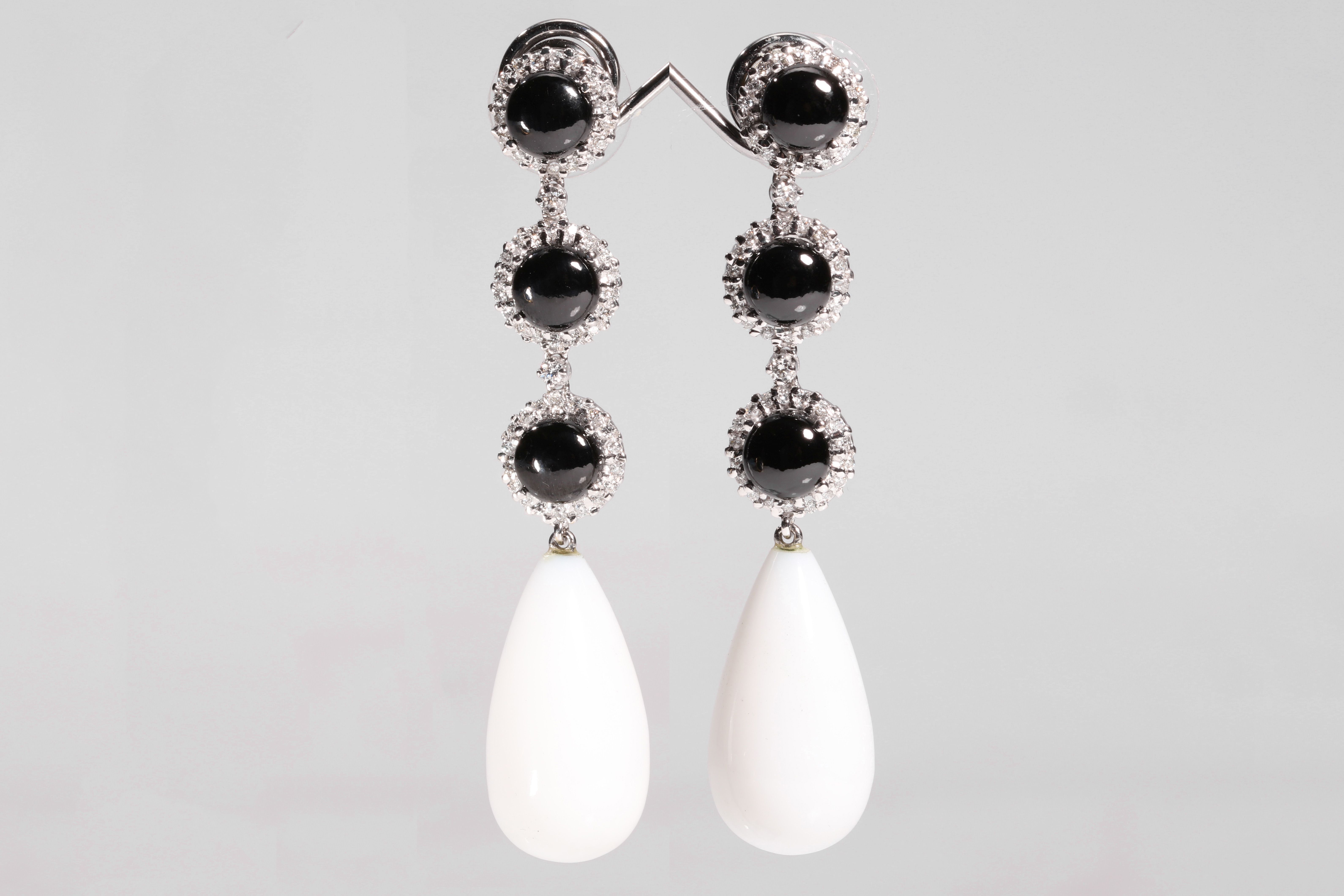 A pair of onyx, white chalcedony and diamond pendent earrings The graduated trio of circular