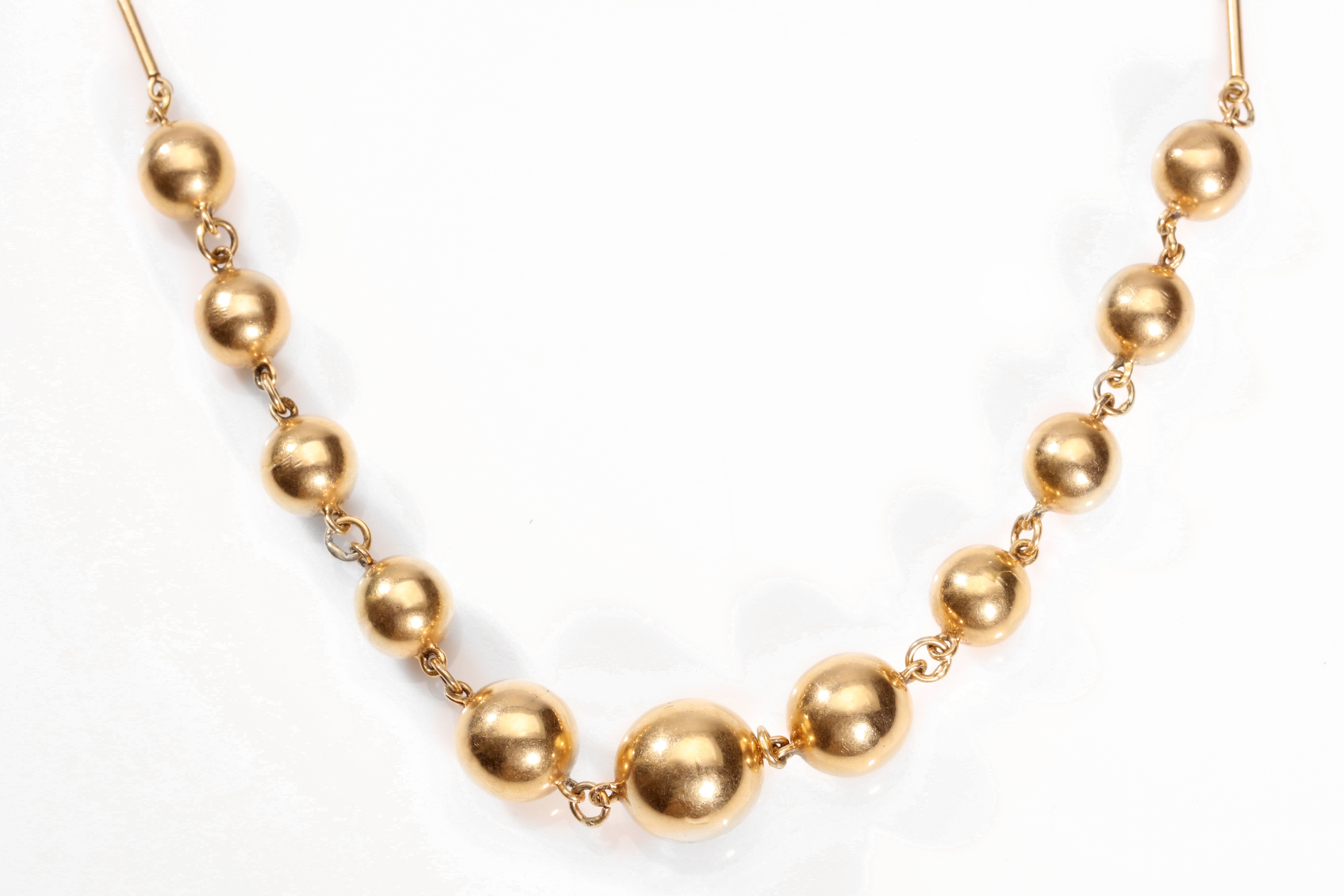 A ball necklace The baton-link necklace, set to the front with graduated polished ball accents,