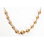 A ball necklace The baton-link necklace, set to the front with graduated polished ball accents,