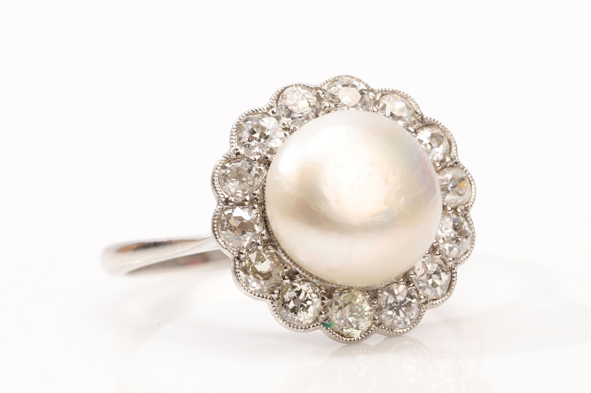 A natural pearl and diamond ring The 9.5mm bouton pearl, within an old brilliant-cut diamond
