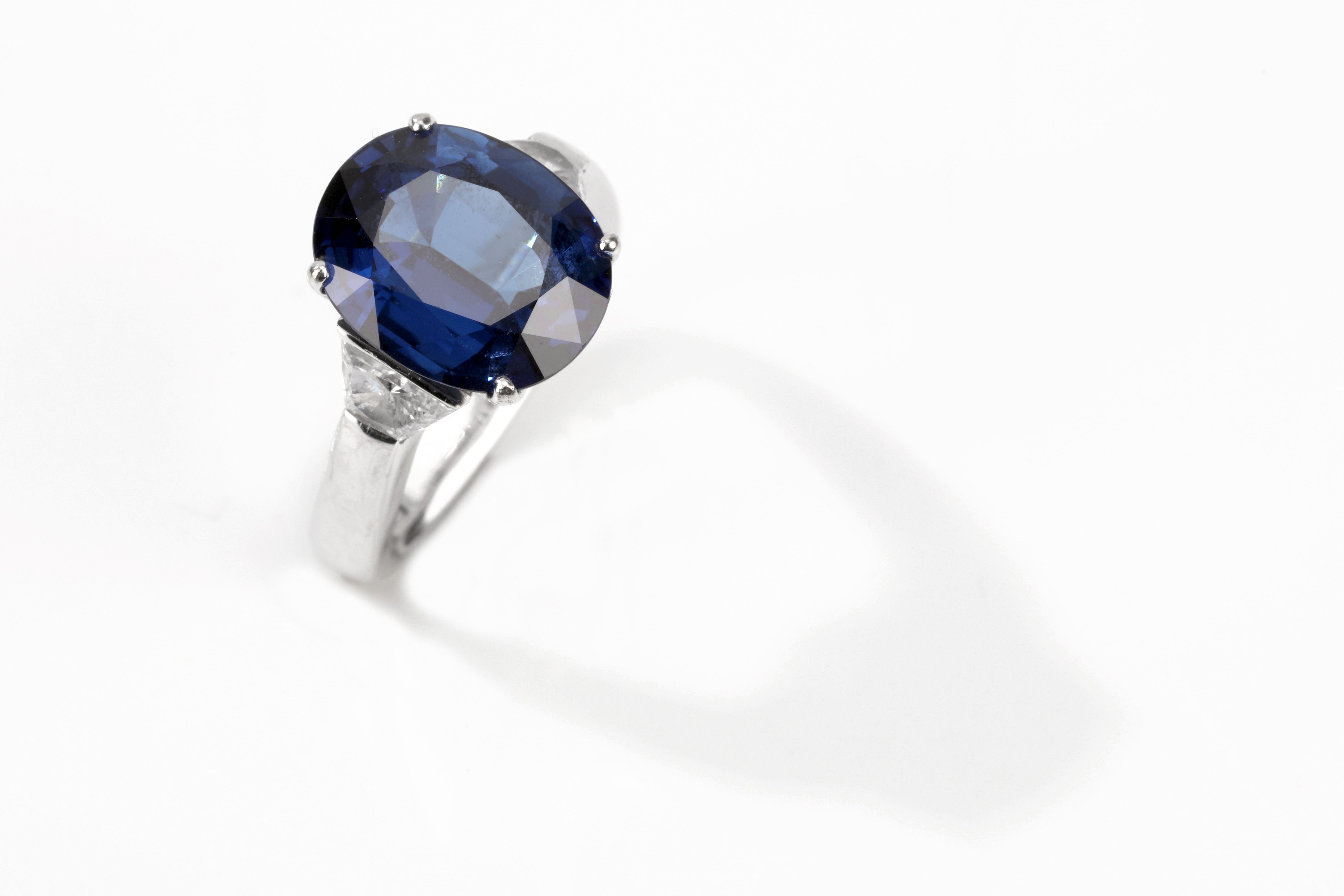 A sapphire and diamond ring The oval-cut sapphire, weighing 6.96 carats, in a four-claw setting,