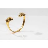 A gold bangle with animal head terminals The 18 carat yellow gold bangle, each end terminating in