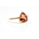A pink tourmaline and diamond cluster ring The orange-pink triangular-cut tourmaline, within a