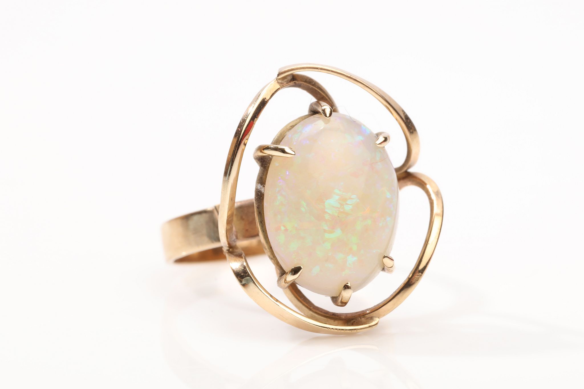An opal dress ring The swirling openwork gallery, centrally featuring an oval-cut opal, ring size