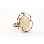 An opal dress ring The swirling openwork gallery, centrally featuring an oval-cut opal, ring size