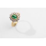 An emerald and diamond cluster ring, 1989 The collet-set oval-cut cabochon emerald, within a