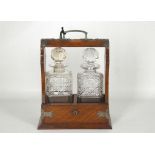 A 1930's oak cased, two section crystal cut glass tantalus with a key.