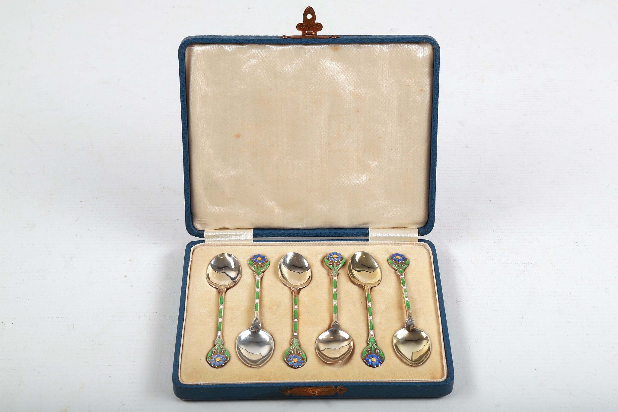 A cased set of Art Deco, hallmarked silver teaspoons, having green and blue enamel flowery