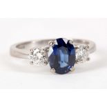 An 18ct white gold , natural sapphire and diamond set three stone ring, the central oval cut