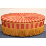 An oval ottoman stool, with striped upholstery.