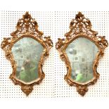 A pair of 18th century Venetian giltwood wall mirrors, the cartouche shape mirrors carved with 'C'